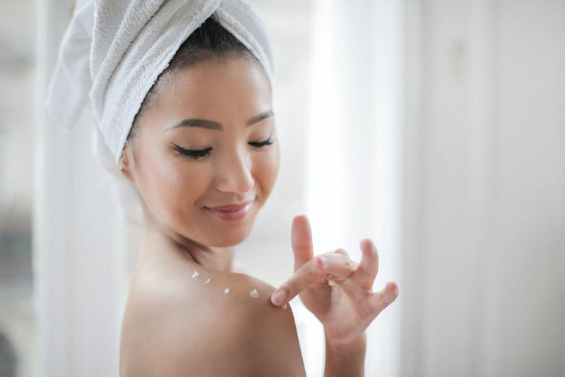 Woman putting body lotion on after going to the spa